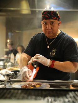 Chef asiatique utilisant un chalumeau pour cuisiner un plat dans un restaurant japonais Seiiki Le Yen.