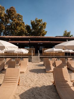 Terrasse extérieure du restaurant Le Yen à Nice avec chaises longues et parasols sur une plage sableuse sous un ciel clair.