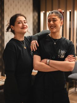 Deux employées souriantes en t-shirts noirs avec le logo Le Yen, restaurant asiatique à Nice, posant à l'intérieur.