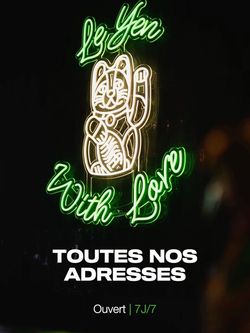 Enseigne lumineuse verte et blanche représentant un chat porte-bonheur avec le texte Le Yen With Love, ouvert 7 jours sur 7.
