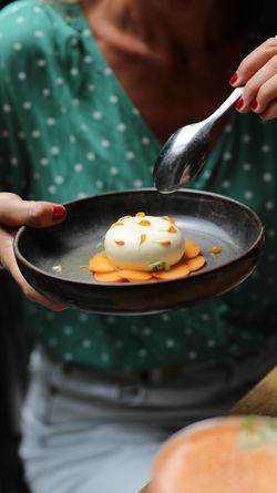 Plat asiatique présenté avec soin, bao blanc sur lit de fines tranches orange avec décorations florales jaunes