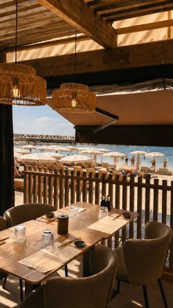Terrasse en bois du restaurant Le Yen Nice avec vue sur la plage et parasols, tables en bois installées pour les clients.