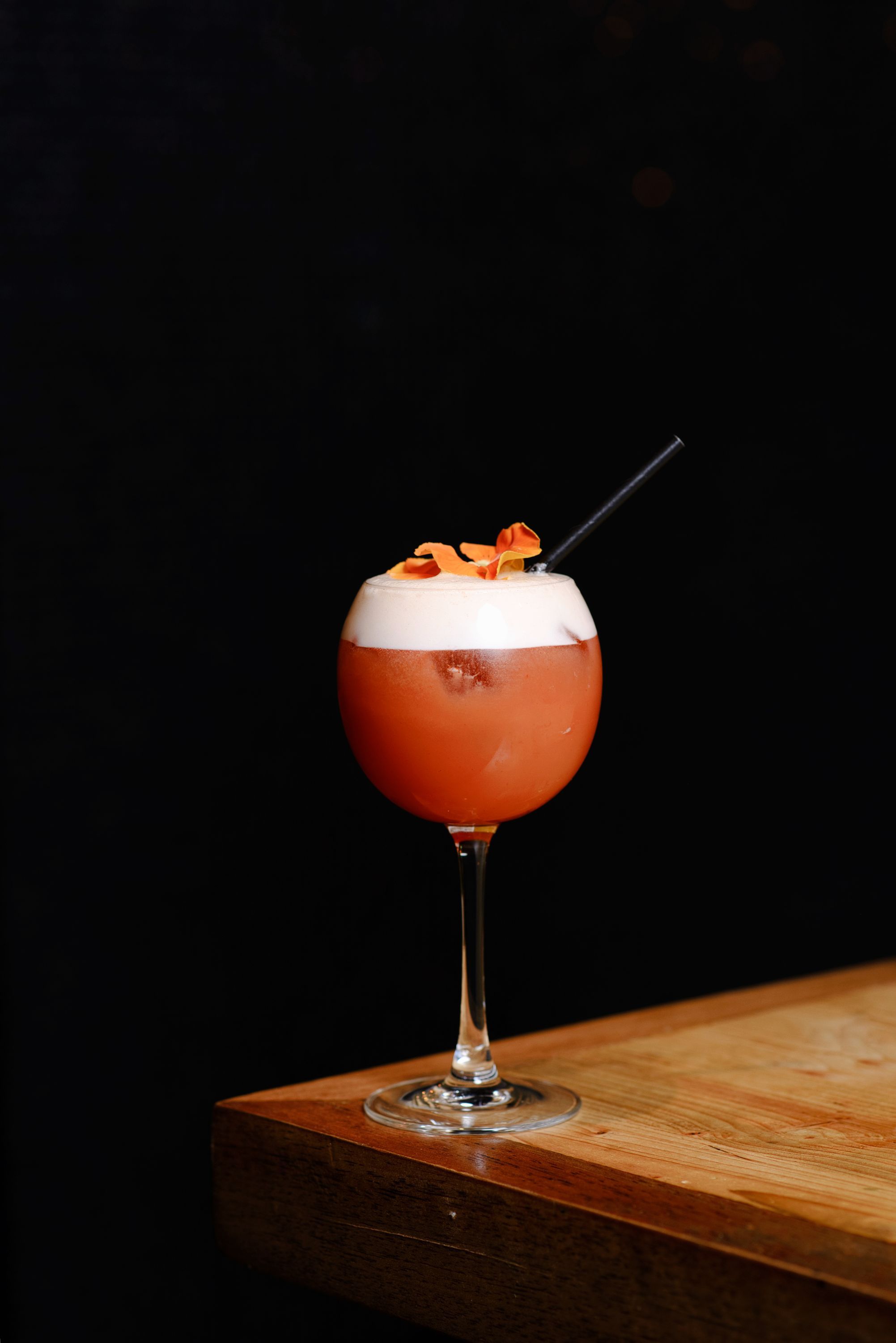 Cocktail frais avec une garniture florale, servi dans un verre à pied élégant.