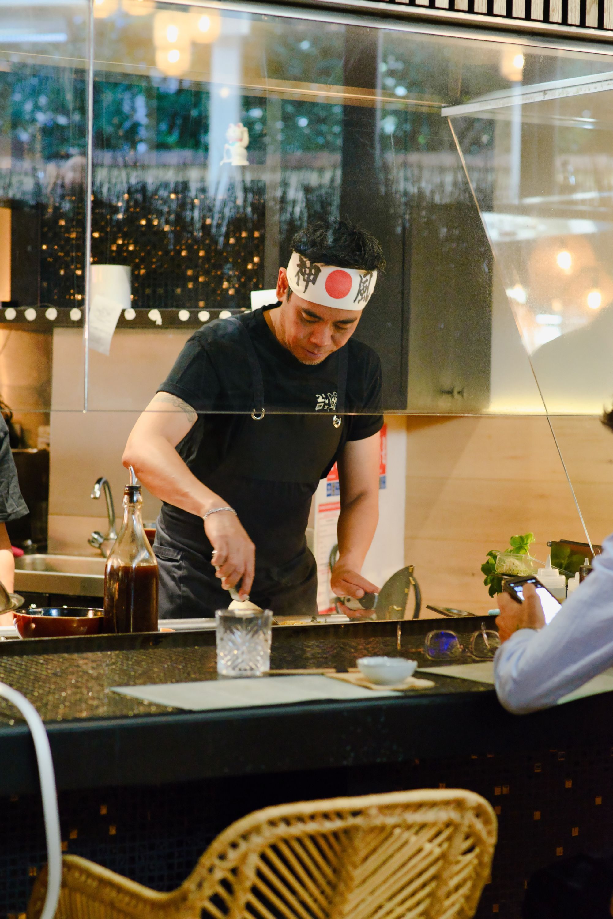 Un chef prépare des plats au comptoir dans un restaurant japonais moderne avec une ambiance accueillante.