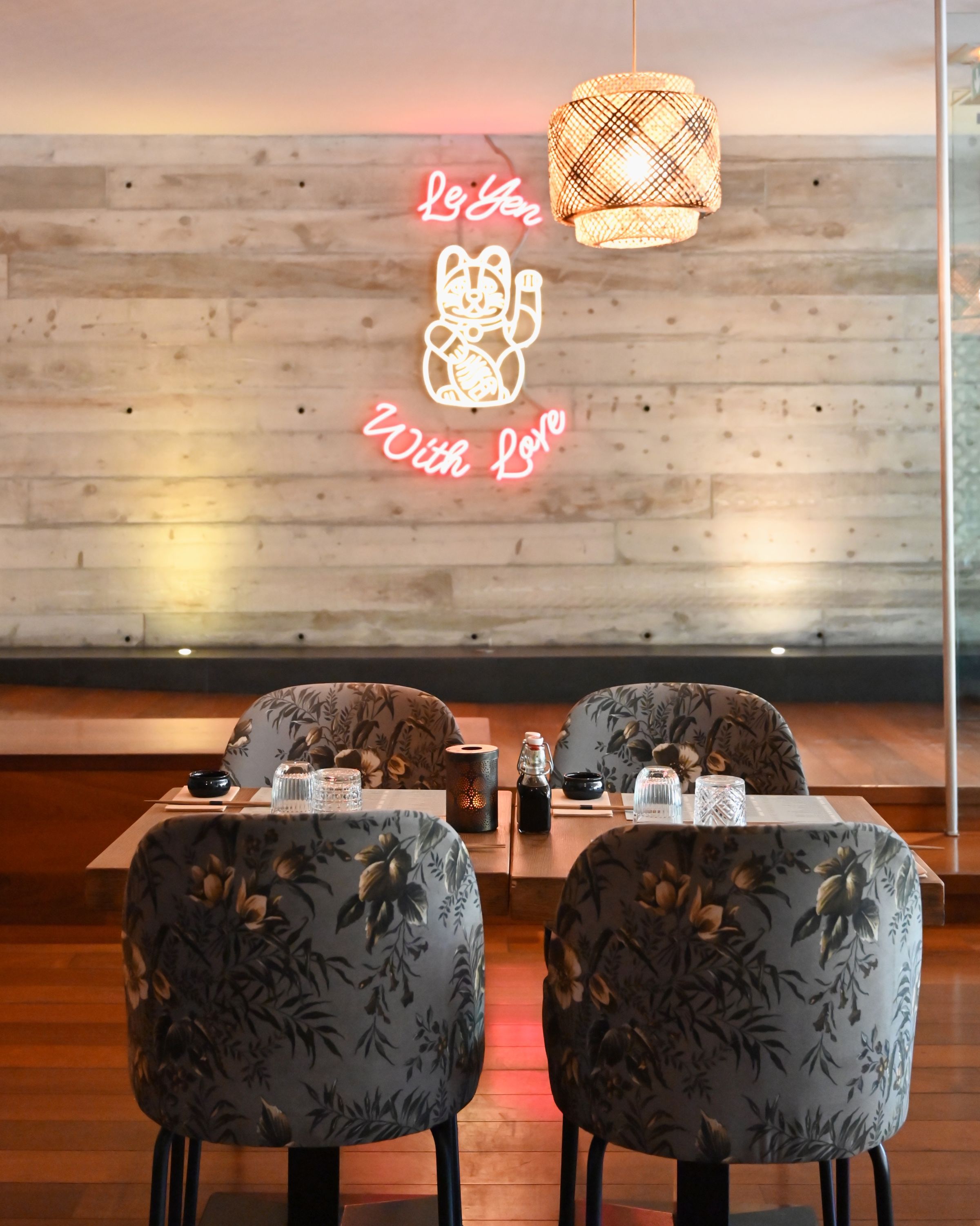 Ambiance chaleureuse au Seiiki Le Yen avec des chaises décorées et une néon lumineux au mur.