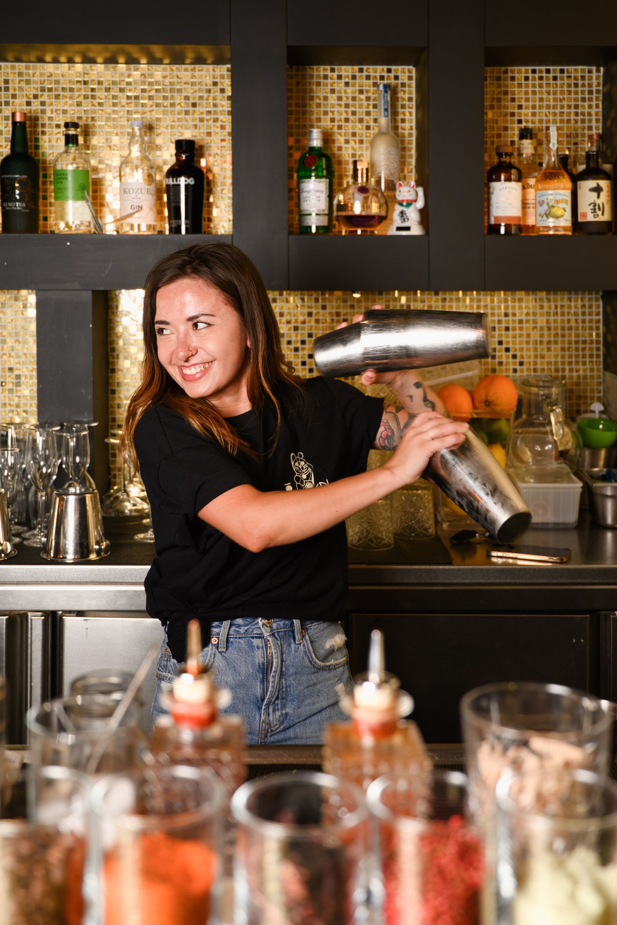 Un barman prépare des cocktails avec un shaker sur le comptoir du bar du restaurant Le Yen Koï.