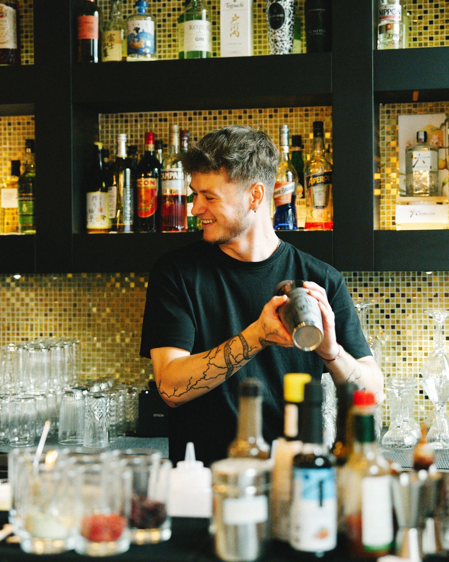 Barman préparant des cocktails au bar du restaurant Le Yen Koï, avec une large sélection de boissons en arrière-plan.