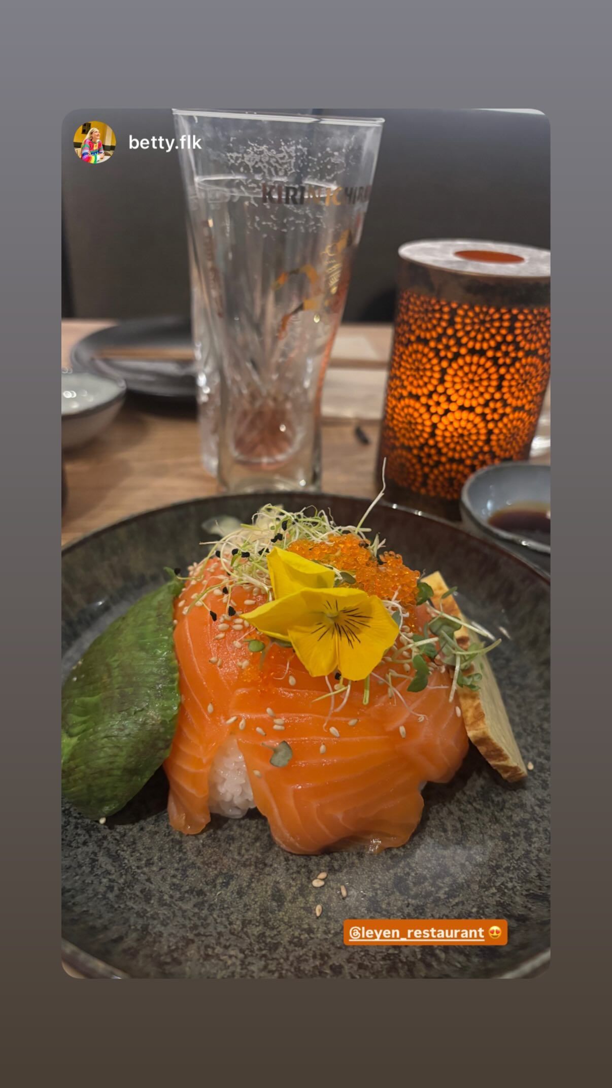 Assiette de sashimi de saumon avec garnitures végétales dans un restaurant asiatique.
