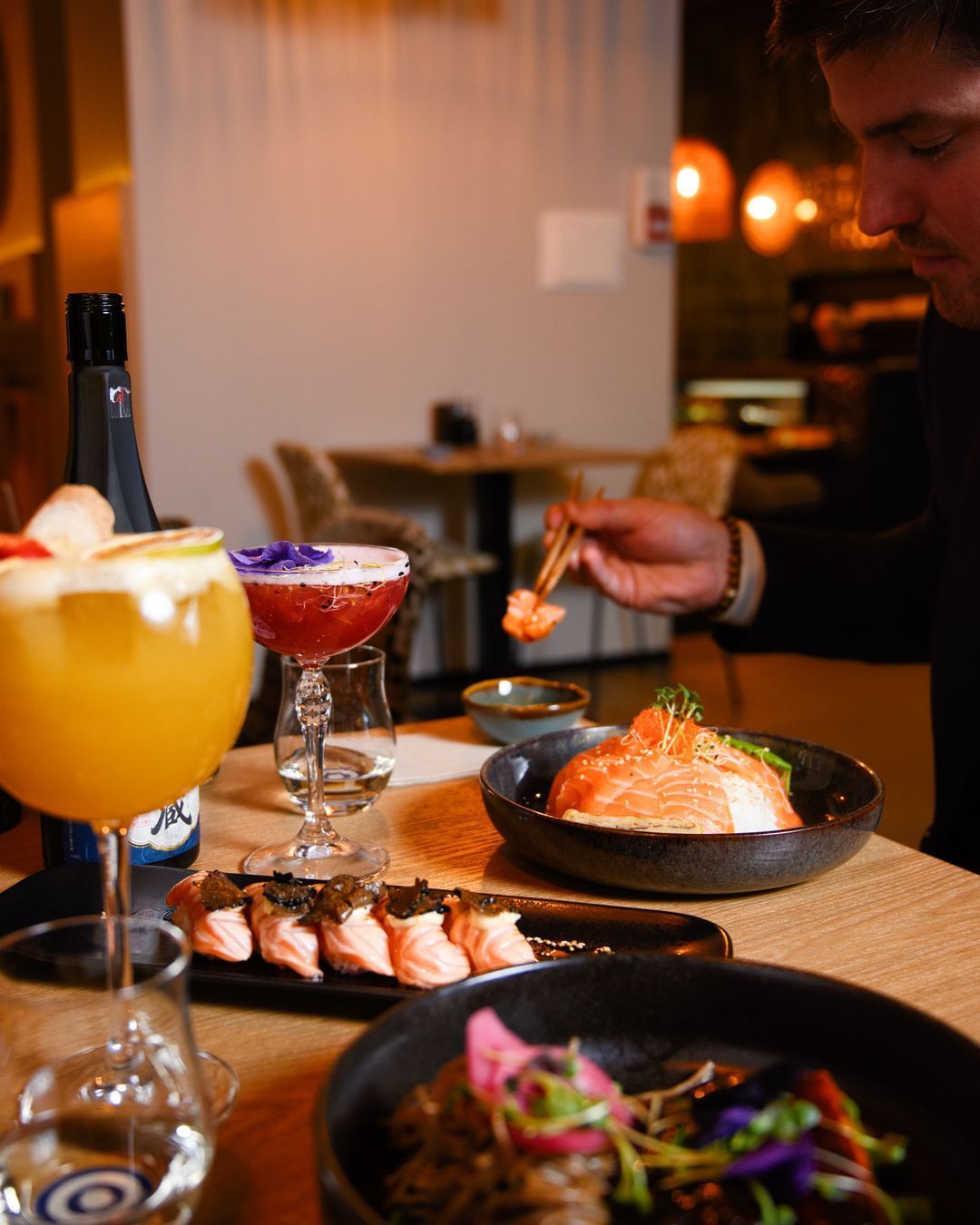 Plats asiatiques présentés, incluant des sushi, des cocktails, et des boissons, dans un cadre élégant.