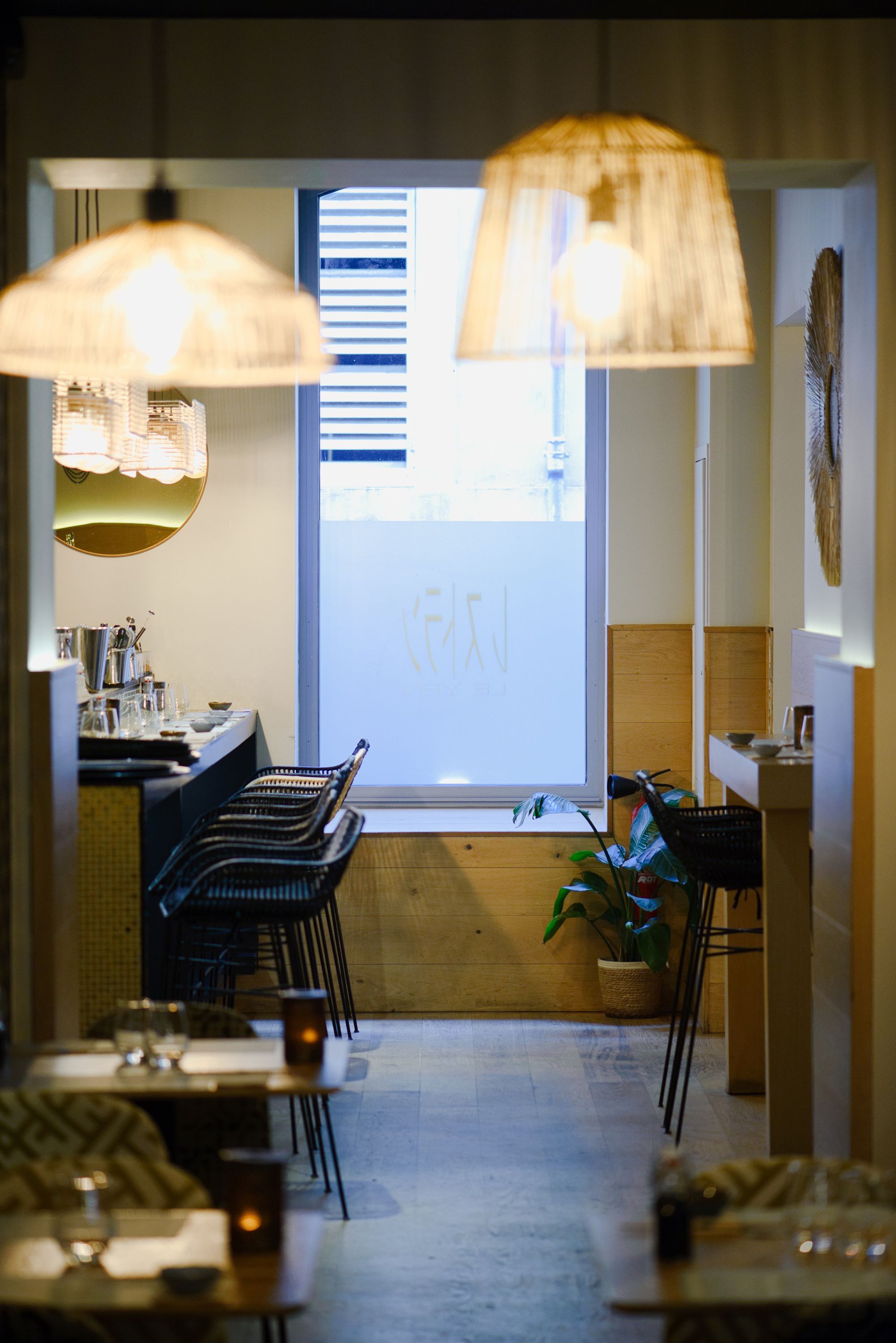 Seiiki Le Yen présente un intérieur moderne avec des luminaires en osier et un bar élégant.