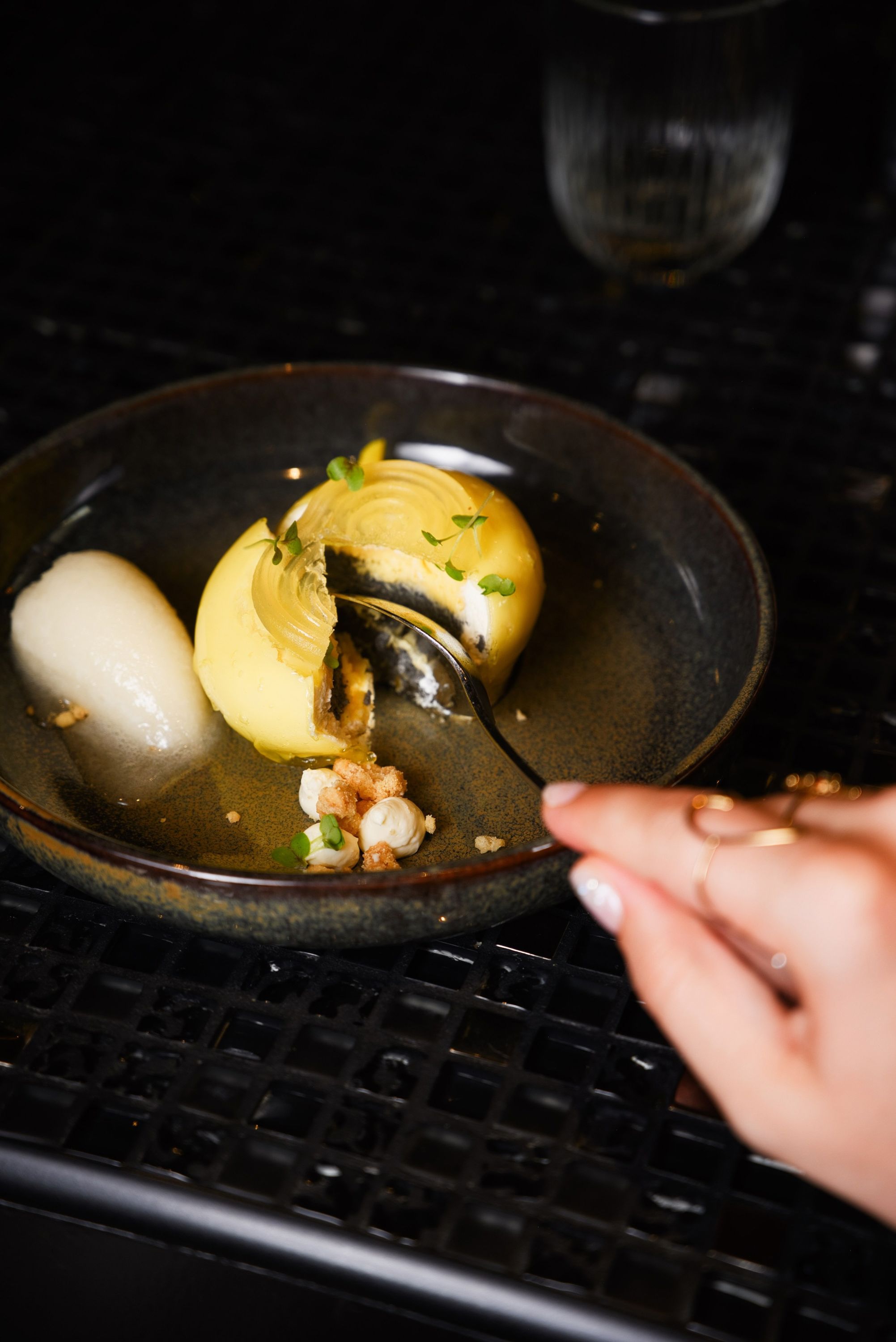 Un dessert délicat servi dans une assiette sombre, accompagné de sorbet et de garnitures.