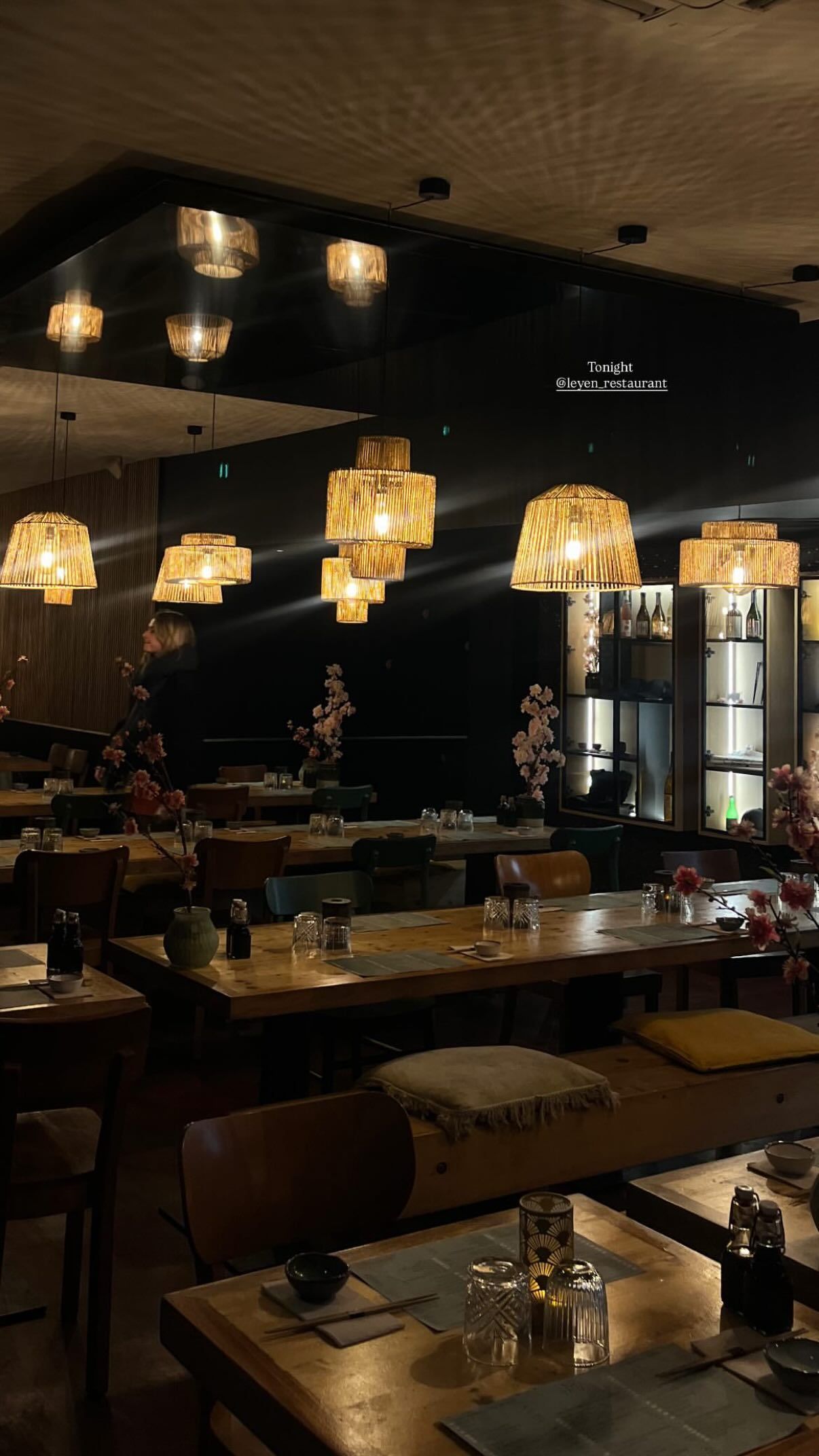 Ambiance chaleureuse du restaurant avec des lampes suspendues et des tables en bois.